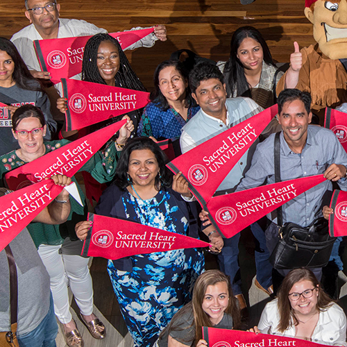 a group of people holding Sacred Heart University pennants