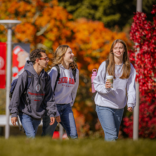 three college students smiling while walking across campus