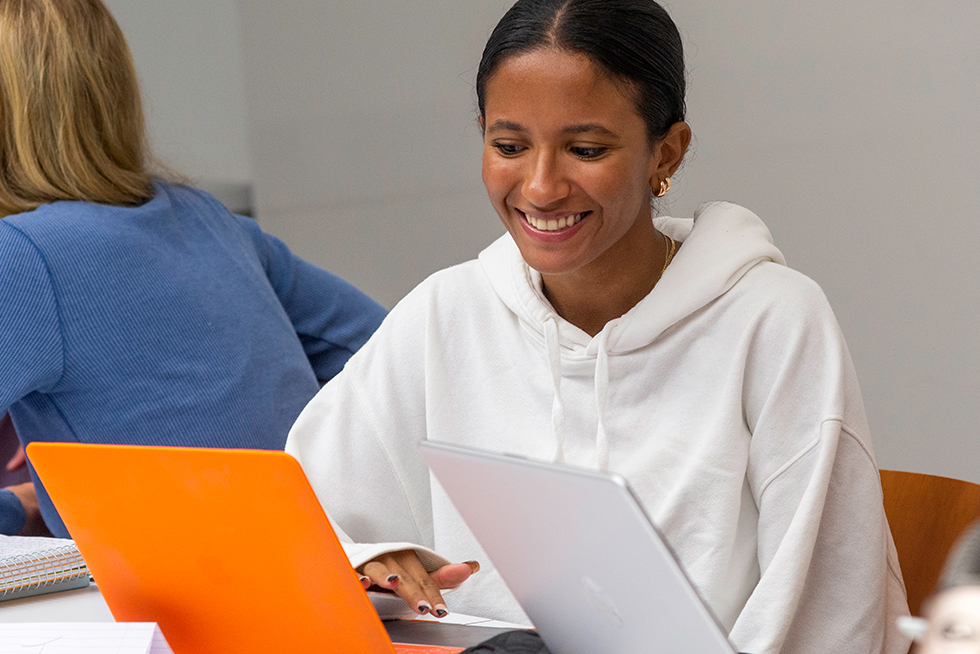 A person smiling while looking at a laptop