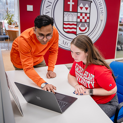 Two college students looking at a laptop computer