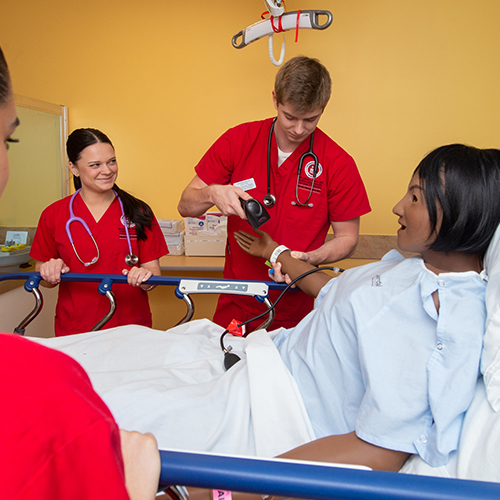nursing students tend to a medical mannequin in class