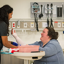 A nursing student practices putting an arm cast on a fellow student