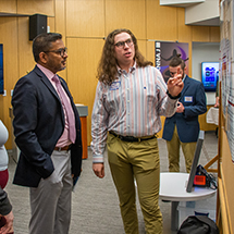 Student explains his research at an academic poster session
