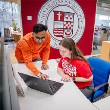 Two college students looking at a laptop