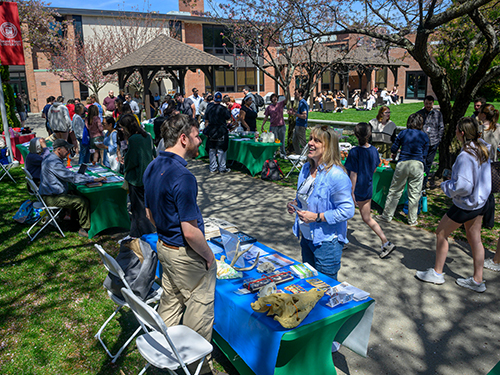 an outdoor Earth Day fair showing people visiting vendor tables