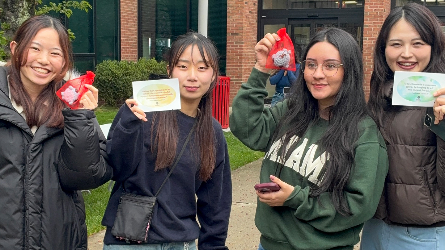 three people standing together holding up cards with quotes from Pope Francis about climate