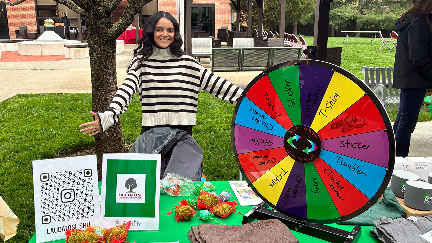 a person working a Laudato Si vendor table and spinning raffle wheel at an Earth Day fair