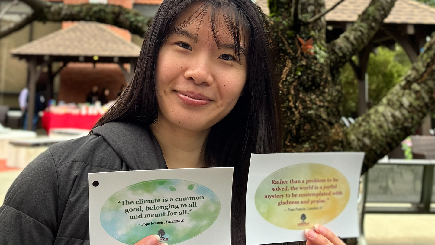 a person holding up cards with quotes from Pope Francis about caring for our common home