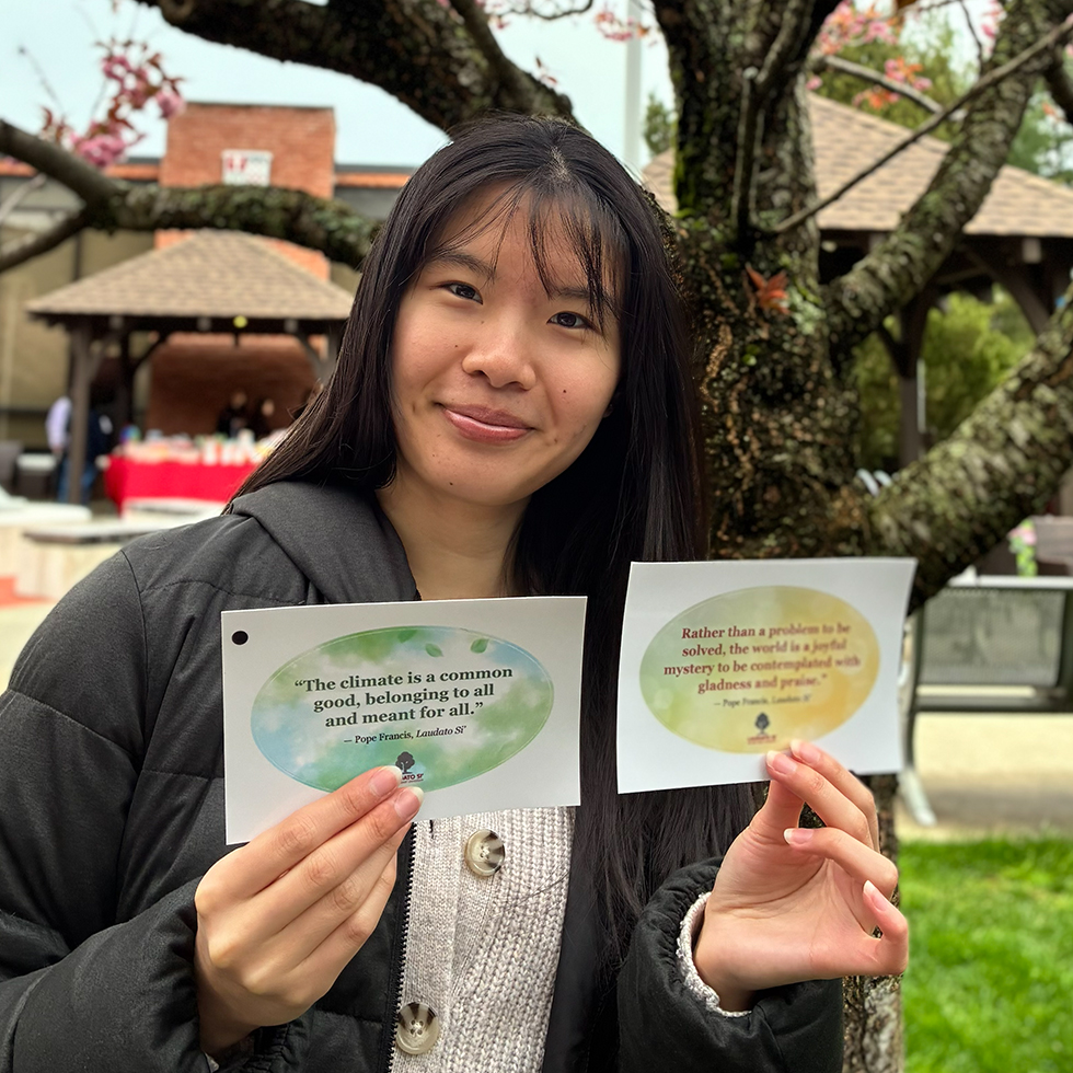a person holding up cards with quotes from Pope Francis about caring for our common home