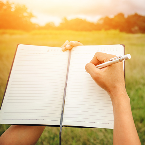an open notebook showing a hand and pen about to write