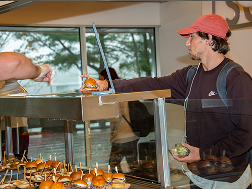 a person taking a burger from a food counter