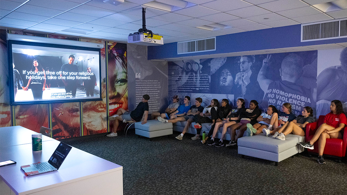 people gathered in a room watching a presentation on a screen