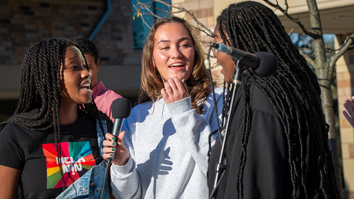 three choir members singing into a microphone
