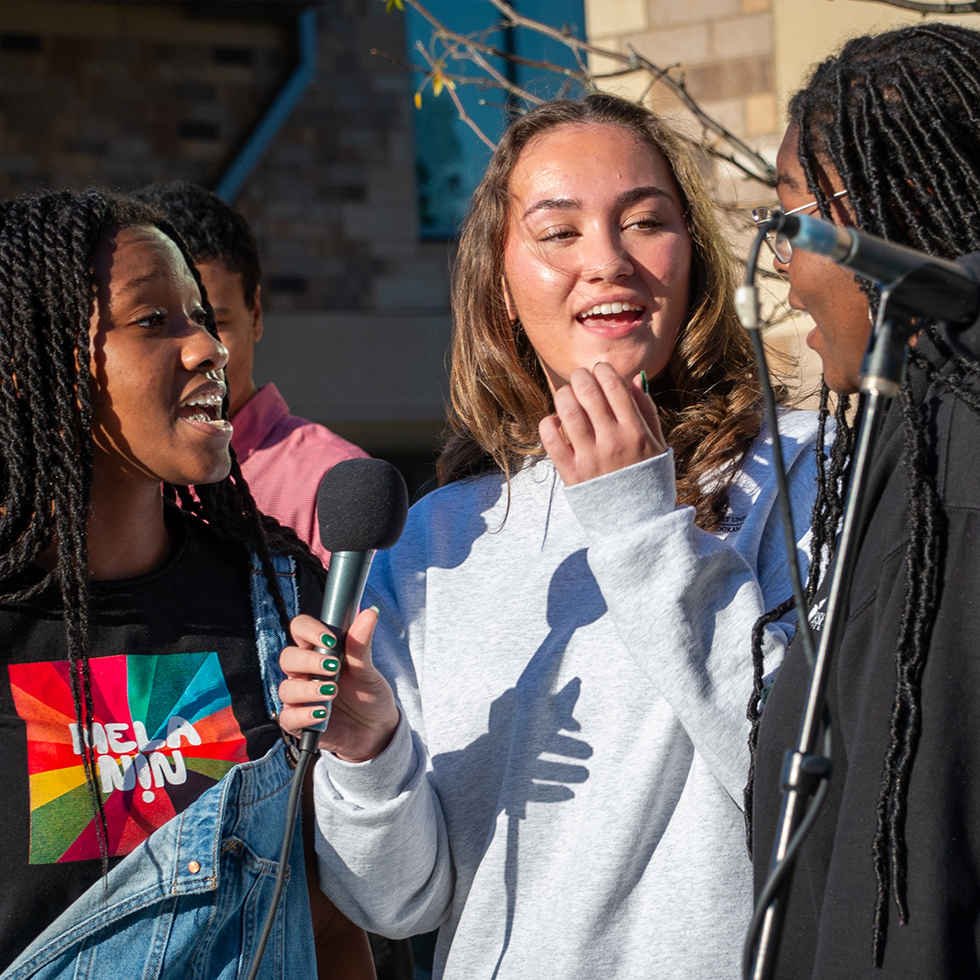 three choir members singing into a microphone