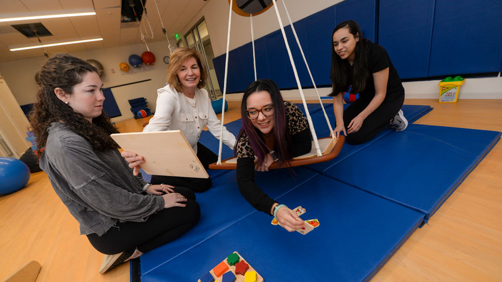 Occupational therapy students using swing and puzzles for therapy