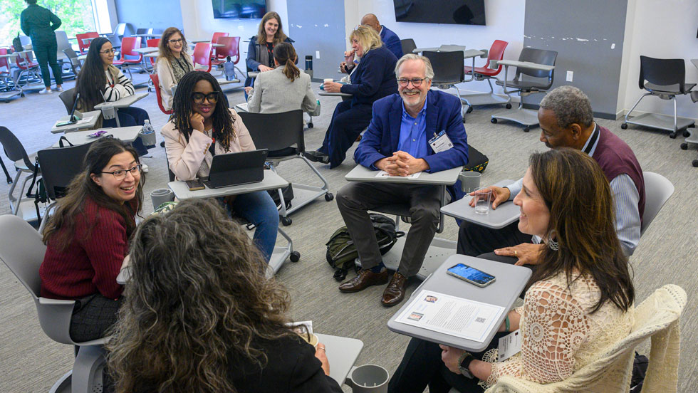 Professionals sitting at desks in a circle in a classroom