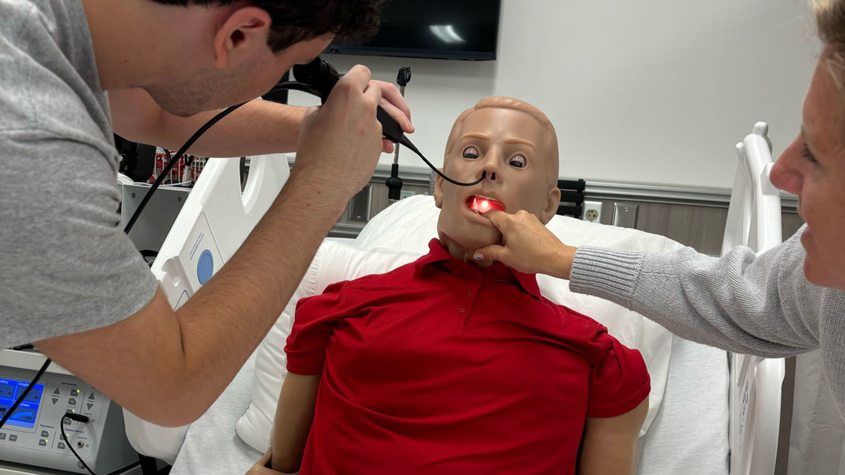 Students looking down throat of a manikin