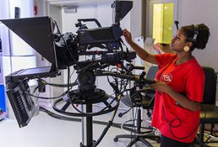 student behind a camera in a video production studio