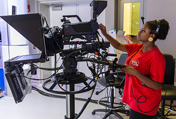 student behind a camera in a video production studio