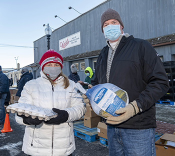 two people holding eggs and a frozen turkey