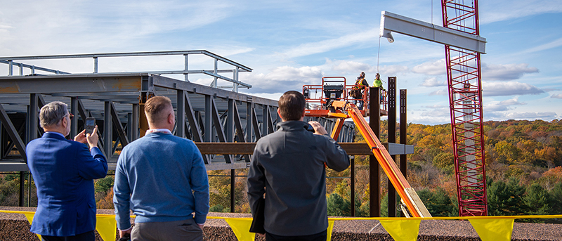 three men watching a construction site