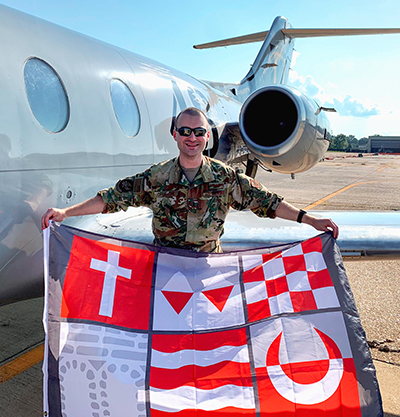 Nick Cavallone holding a SHU flag in front of a plane