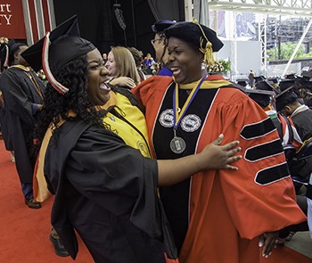professor and student hugging at commencement