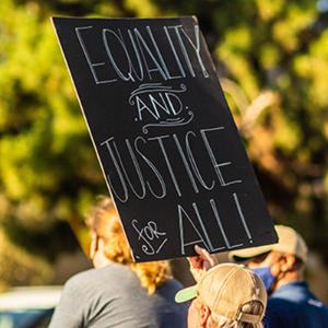 woman holding a equality and justice for all sign