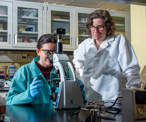 Student & Professor Looking into Microscope in Lab