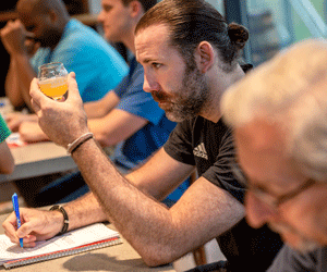 Man looking at cup of beer and taking notes