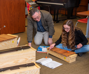 Teacher helping student play xylophone