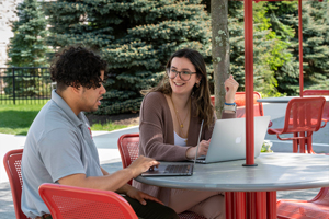 Students sitting outside on laptops