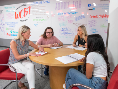 Counselor sitting at table talking to students