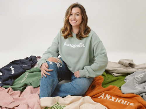 Sophie Nistico sitting amongst sweatshirts