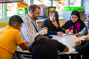 Teacher working with group of students at table in classroom
