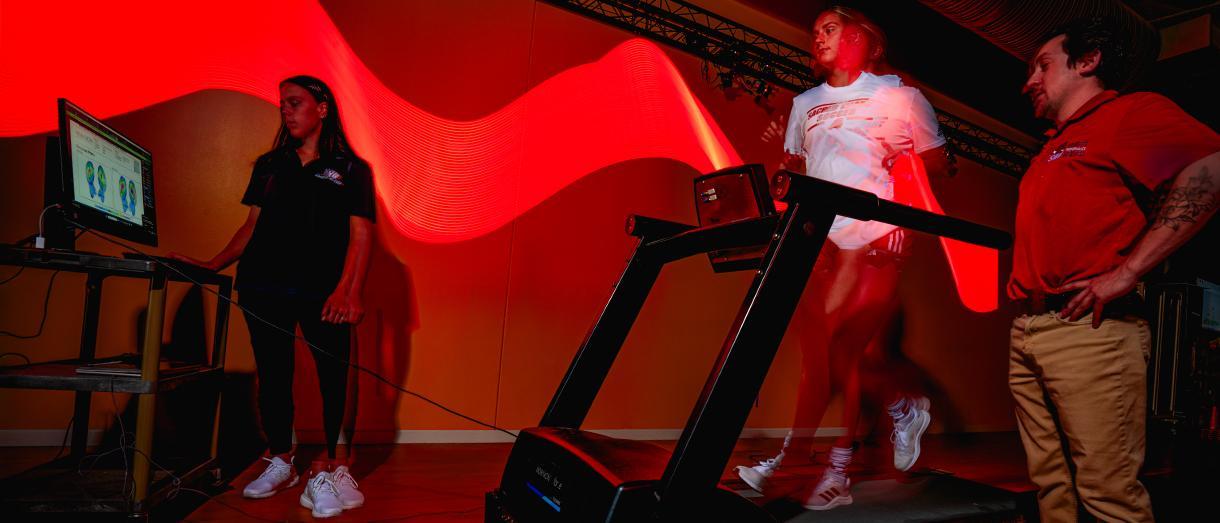 Person running on a treadmill with exercise scientists monitoring