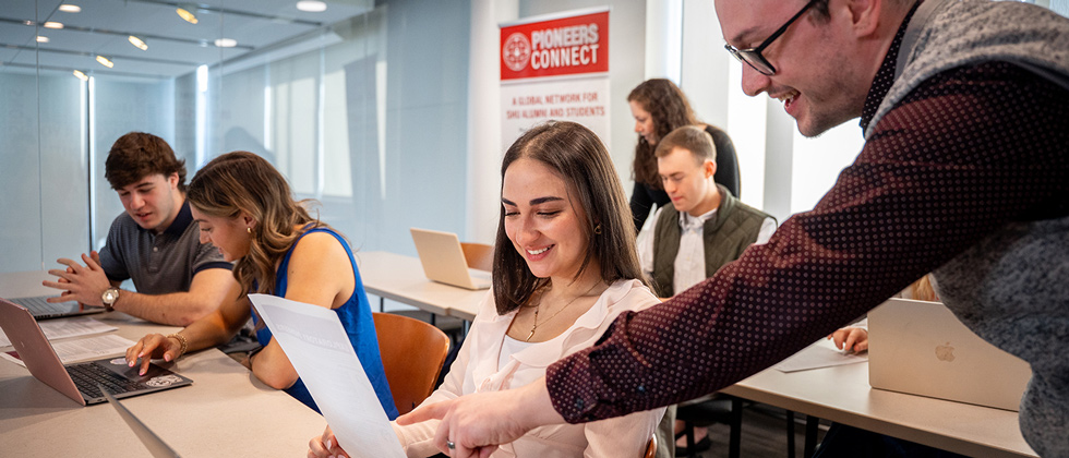 Professor pointing at paper in front of student in a classroom