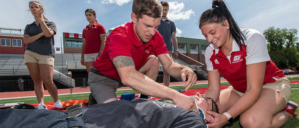 Athletic trainers tending to a patient on a football field