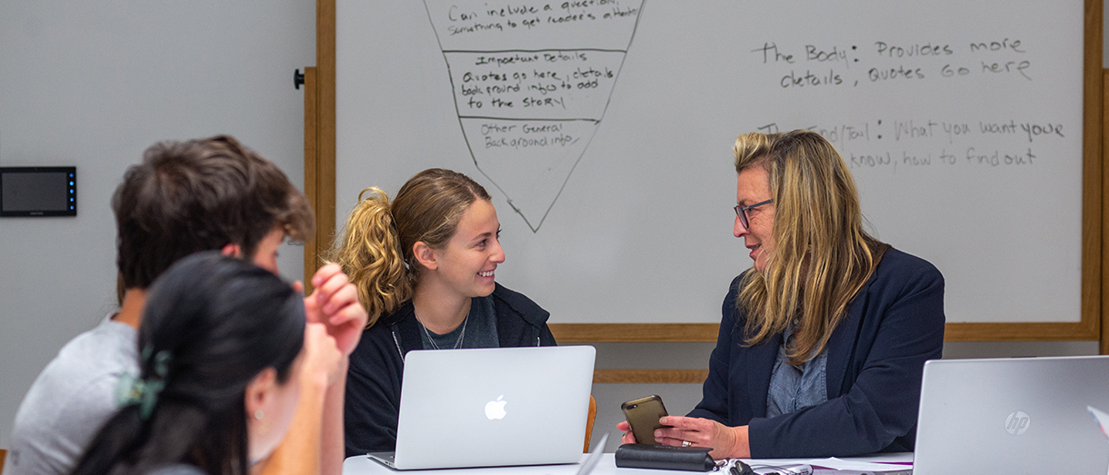 A professor teaching students on laptops