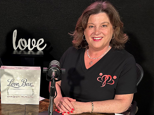 A woman sitting at a microphone next to a Love Box