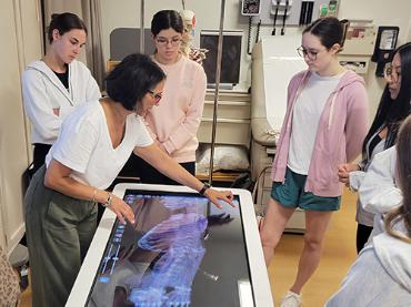 A professor shows a group of students muscle structure on an anatomage table