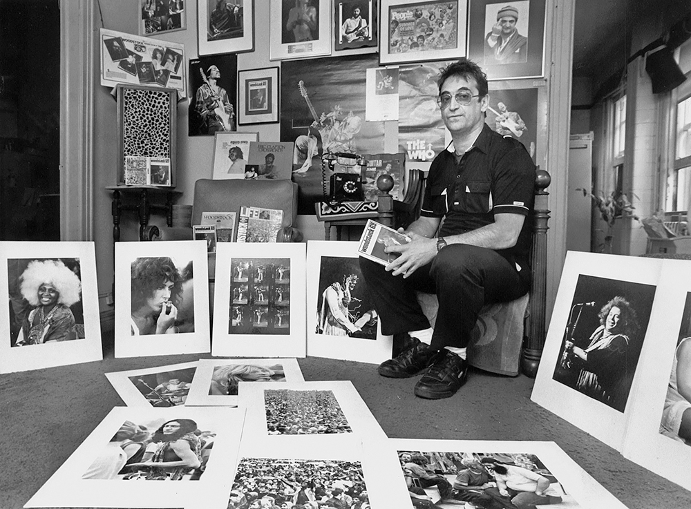 Joe Sia sitting with his photograph prints