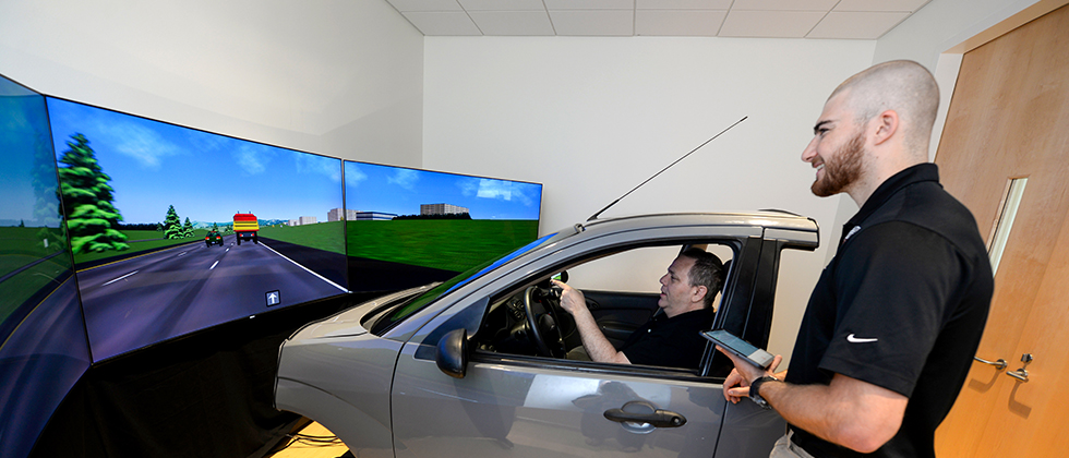 Student observing patient in the driving simulator