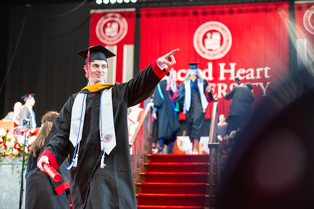 Graduate pointing to his family after receiving diploma
