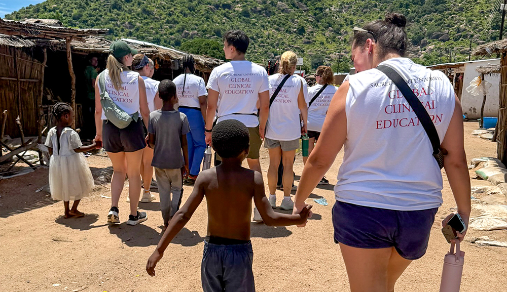 Nursing students holding hands with children in the community