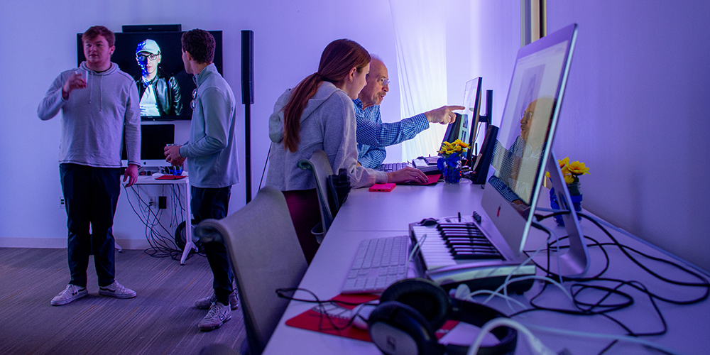 A college professor instructing a student at a computer