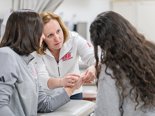 Professor showing students something on a students hand in AT Lab