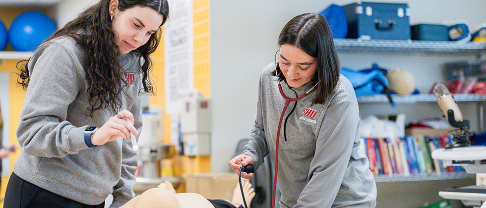 Athletic training students practicing on manikin in AT Lab