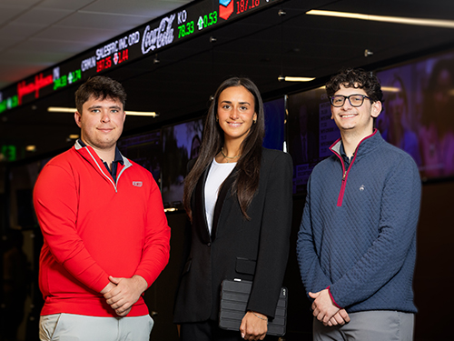 Business students standing in front of stock ticker tape