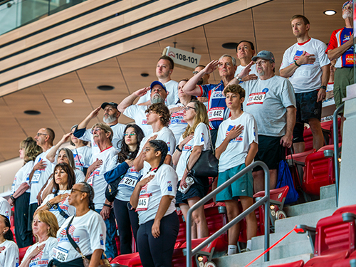 People standing in an arena saying the pledge of allegiance